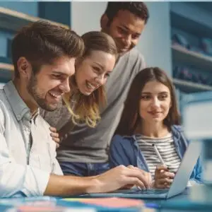 Vier junge Menschen schauen auf einen Laptop.